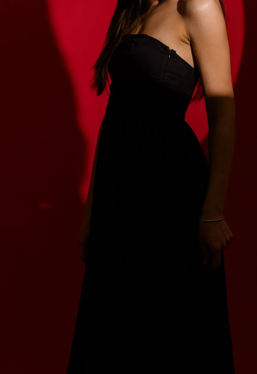 Look femenino elegante en negro, con fondo rojo