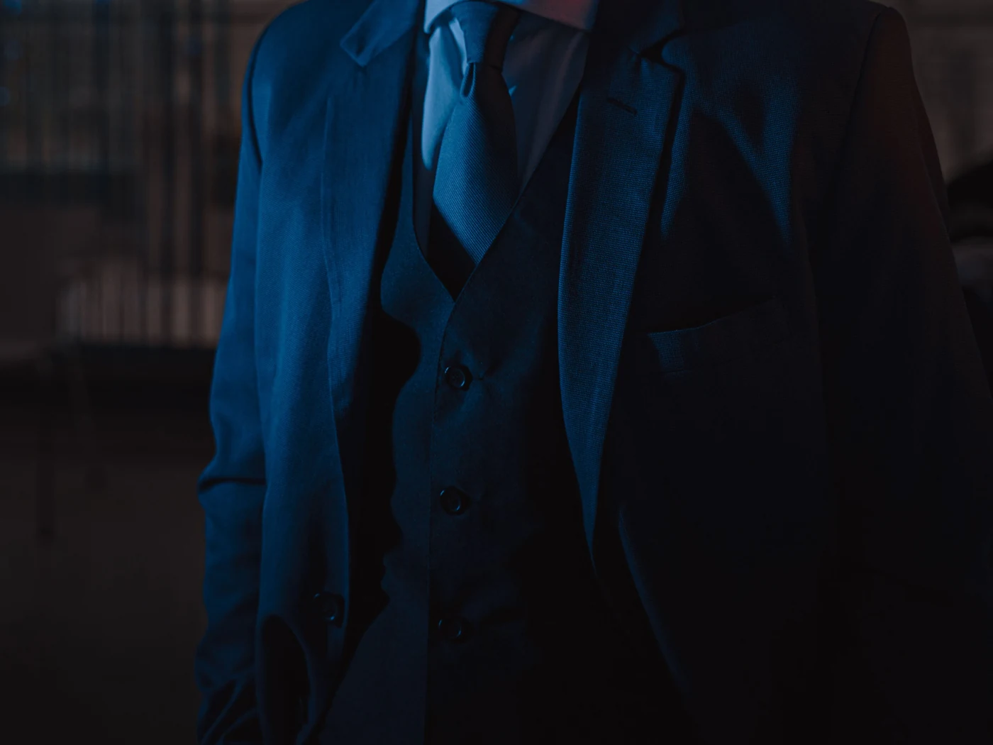 Detalle de traje oscuro, chaleco y corbata, sin mostrar el rostro